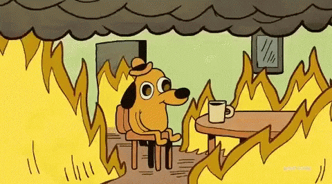 Cartoon dog sitting at a table in a room engulfed in flames, calmly saying 'this is fine.'